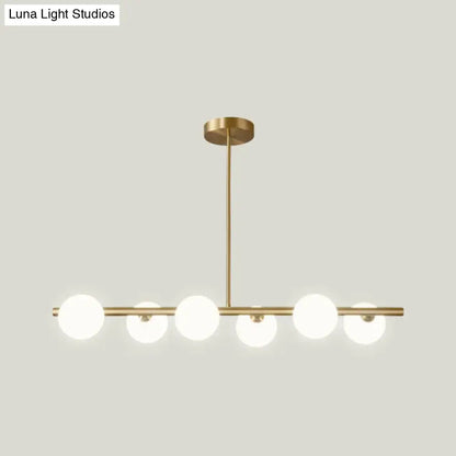 Modern brass 5-light pendant light with spherical glass shade featuring frosted globes in a dining room setting
