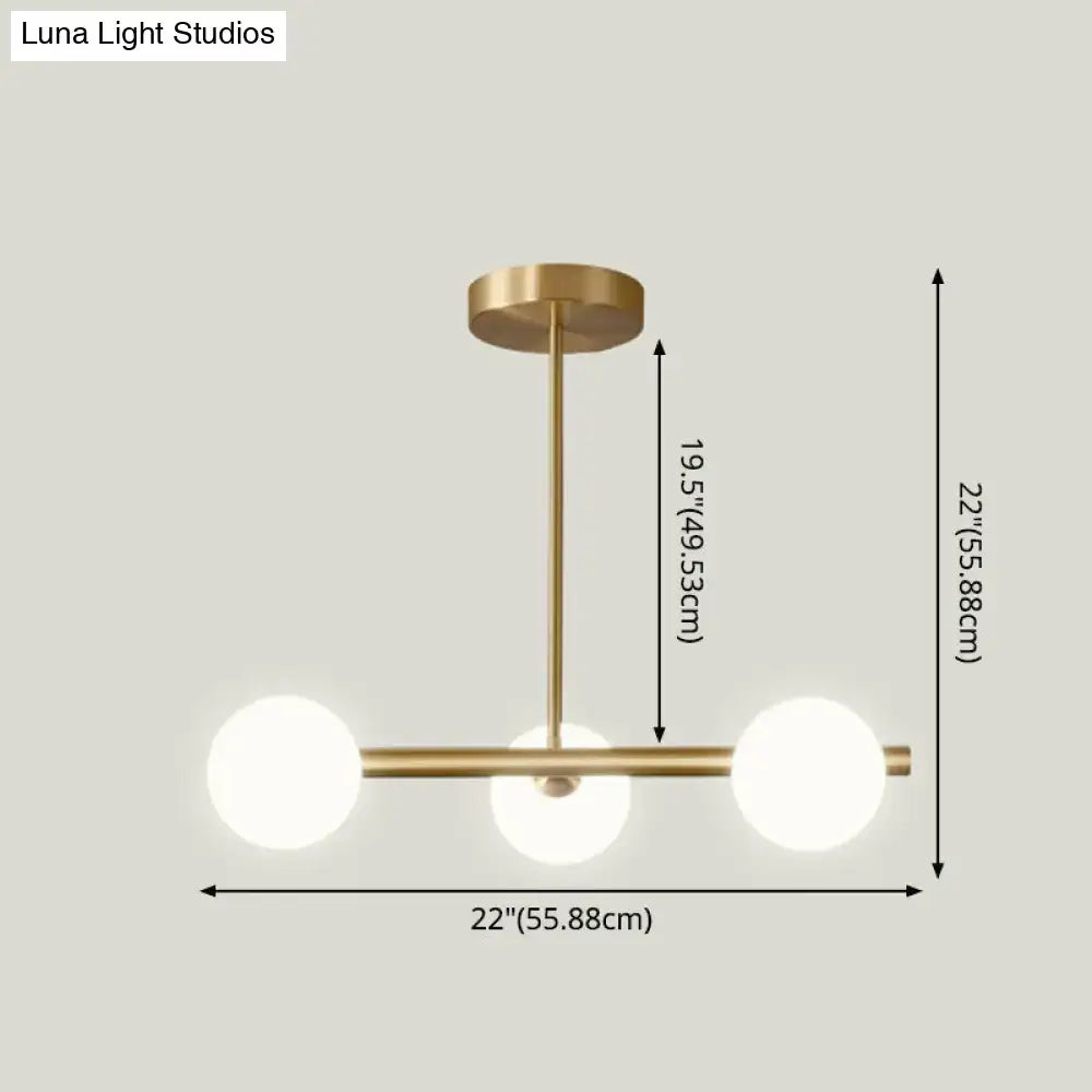 Modern brass pendant light with three spherical glass shade bulbs arranged in a horizontal line for dining room use