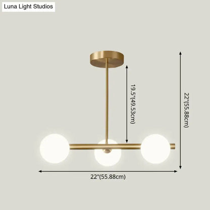 Modern brass pendant light with three spherical glass shade bulbs arranged in a horizontal line for dining room use