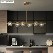 Modern brass pendant light with five spherical glass shades designed for dining room illumination