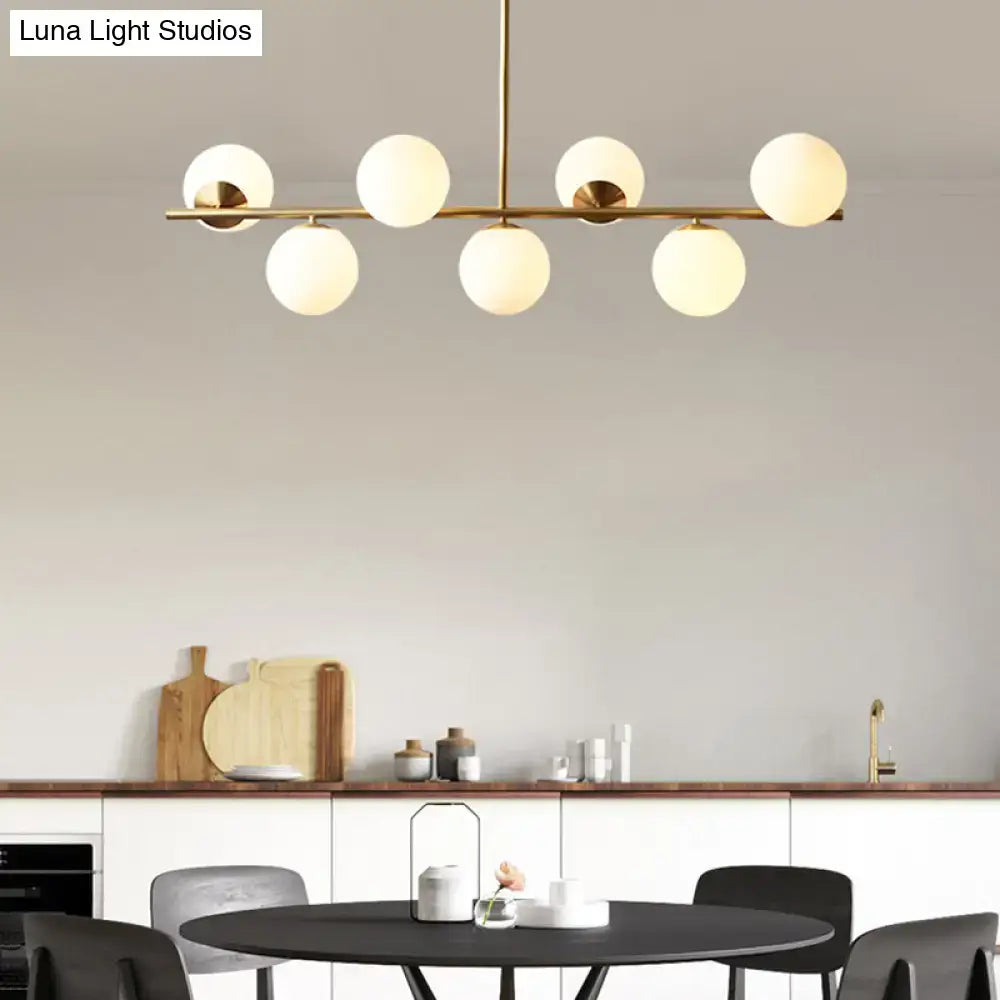 Modern brass pendant light with six frosted glass globe bulbs in a spherical dining room linear design