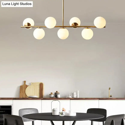 Modern brass pendant light with six frosted glass globe bulbs in a spherical dining room linear design