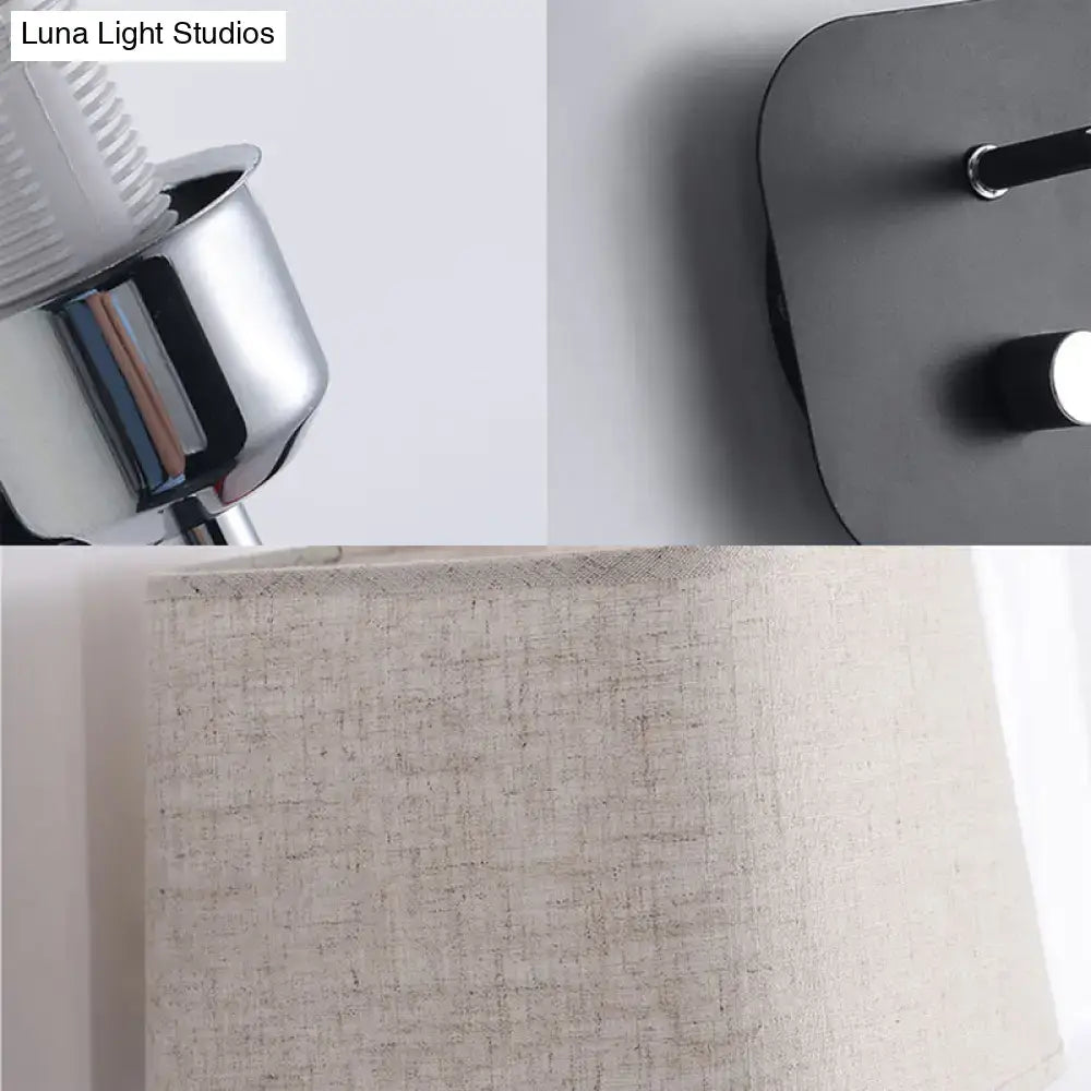 Modern beige linen wall sconce lighting with sleek chrome-finished base and black wall-mounted fixture for bedroom use