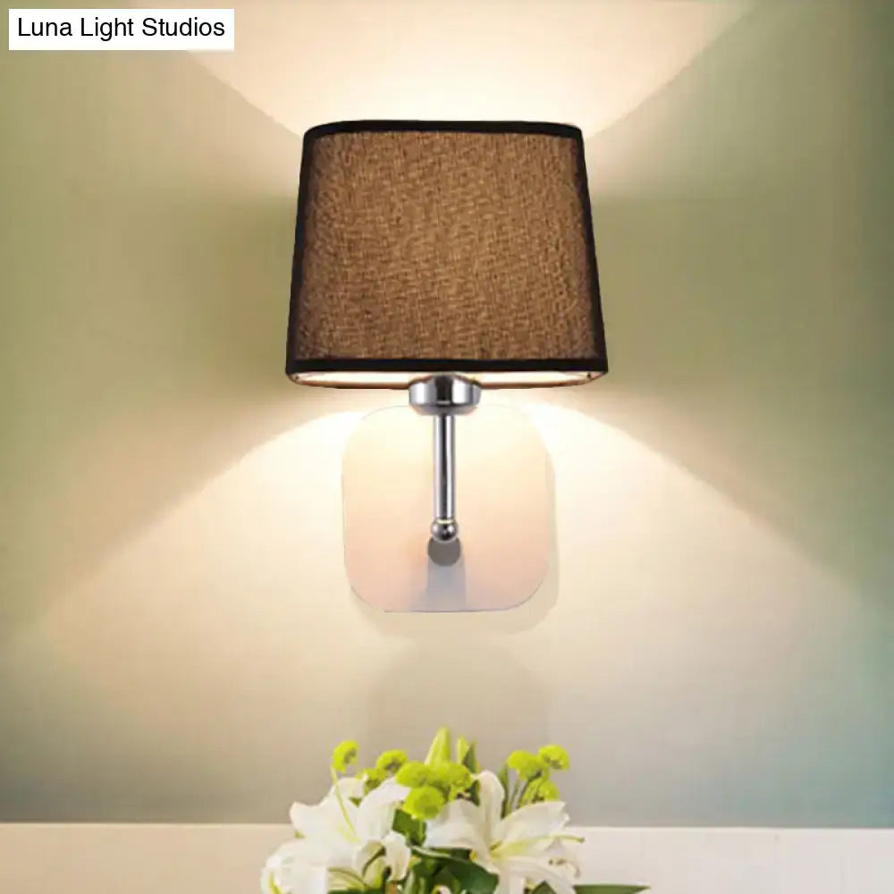 Modern beige linen wall sconce lighting with a square brown fabric shade and chrome metal stem for bedroom use