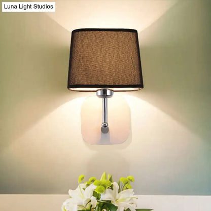 Modern beige linen wall sconce lighting with a square brown fabric shade and chrome metal stem for bedroom use