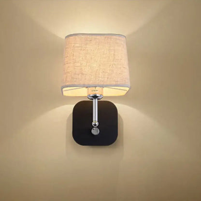 Modern wall sconce lighting with a square black base, chrome stem, spherical accent, and beige linen fabric shade