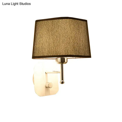 A modern brass and beige linen wall sconce with a textured fabric shade and polished metallic arm for sconce lighting