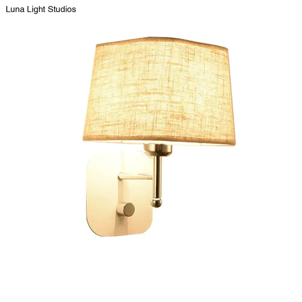 Modern brass and beige linen wall sconce lighting with warm-toned textured fabric and adjustable arm for bedroom use