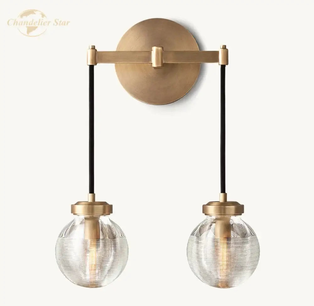 Modern brass and black crystal led wall sconce with two textured glass globes suspended by black cords for bedroom lighting