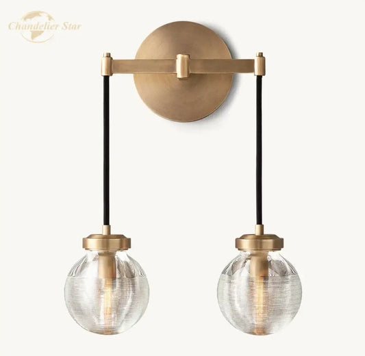Modern brass and black crystal led wall sconce with two textured glass globes suspended by black cords for bedroom lighting