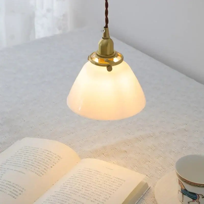 Modern brass and clear glass chandelier pendant light with warm-toned translucent glass and twisted brown cord for dining room