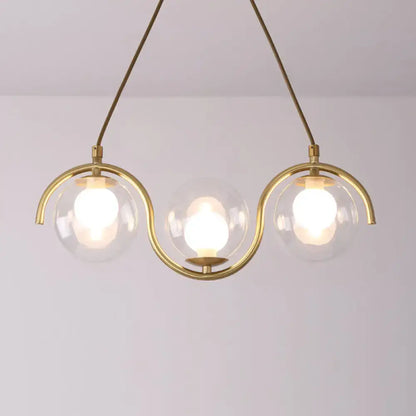Modern brass and clear glass globe pendant light with three clear glass shades and adjustable chain cord length fixture width
