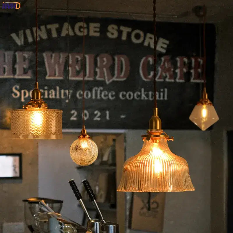 Three modern brass pendant lights with clear glass led amber shades featuring fluted spherical and faceted designs