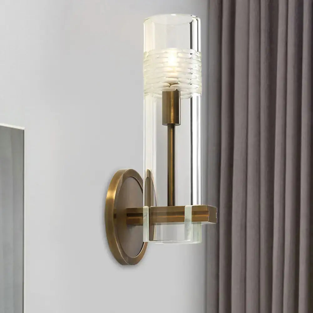 Modern brass and clear glass metal arm sconce with textured frosted band for bedroom wall light featuring clear glass bulb wall design