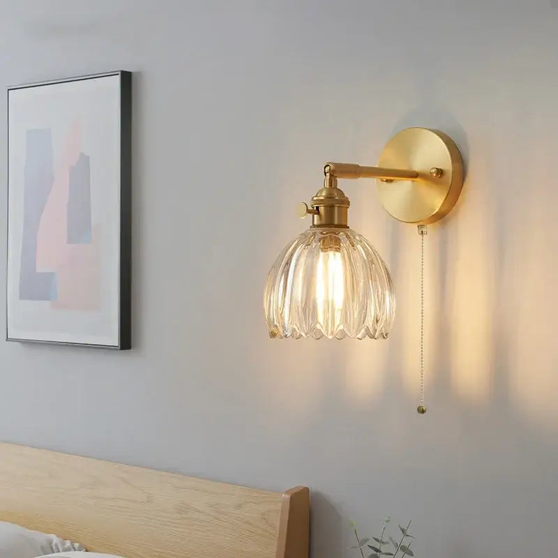 Gold-finished modern brass wall light with faceted clear glass shade and pull chain for bedroom decorbites clear glass design