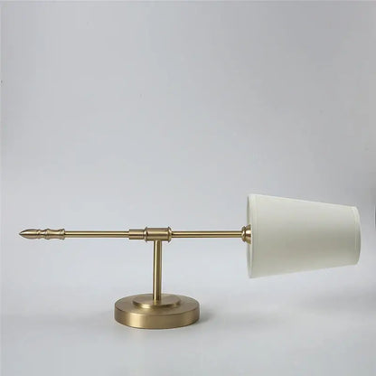 A sleek brass led wall lamp with a minimalist design and tapered cream fabric shade for modern bedroom use