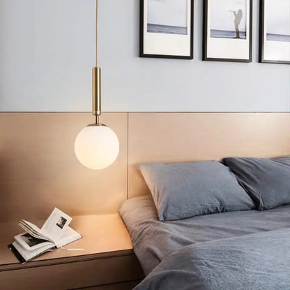 Modern brass and frosted glass pendant light with cylindrical stem and globe shade for dining room chandelier pendant light
