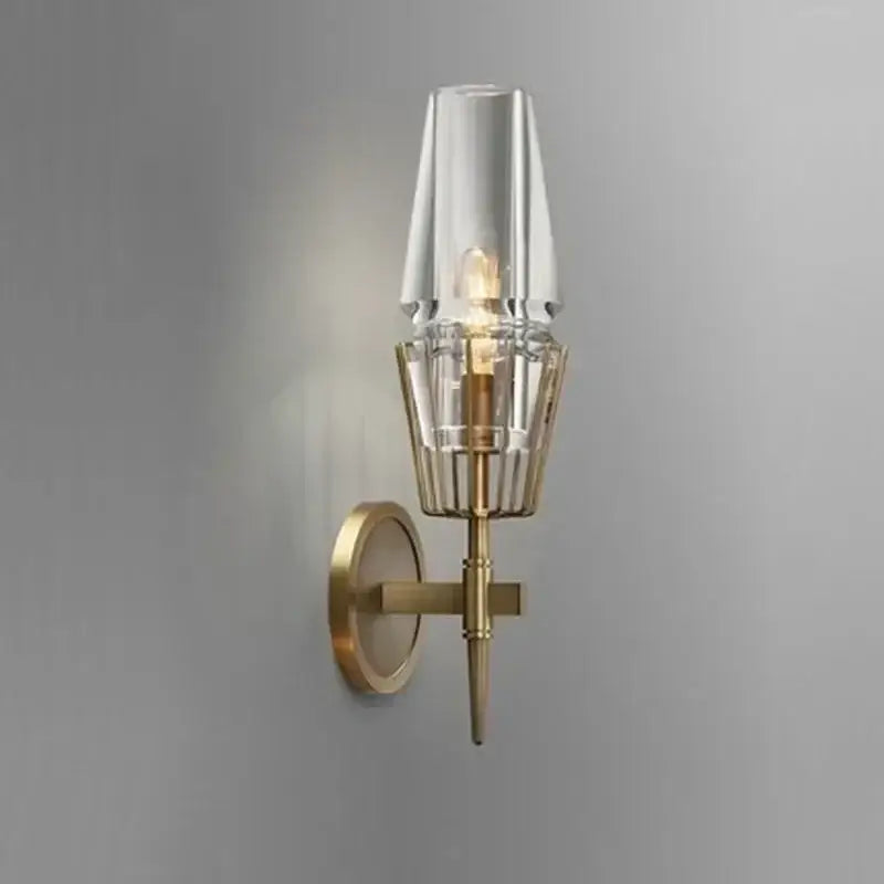 A modern brass and glass bedside table lamp wall sconce with clear glass shade and vertical ridges for bedroom use