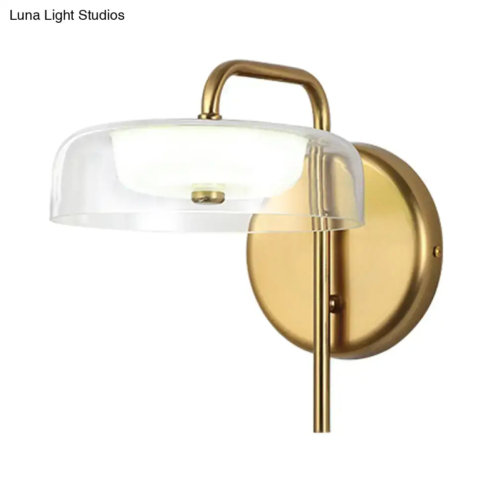 Modern brass and glass bedside wall sconce with clear glass dome and curved arm for bedroom lighting