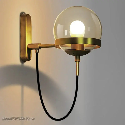 Modern brass and glass globe led wall lamp with spherical glass globe and black cord for bedroom lighting