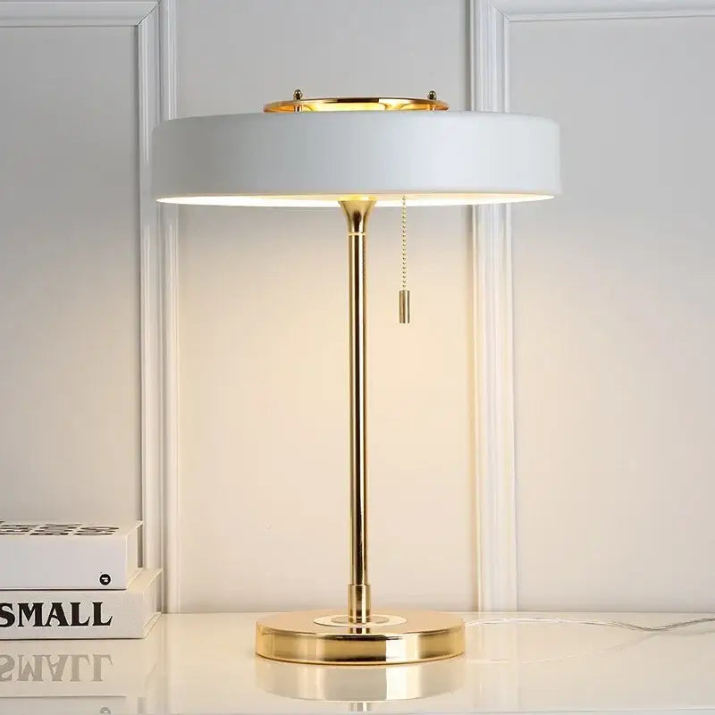 Modern white table lamp with gold-toned metal base and circular shade for warm light in decorbites scandinavia lighting