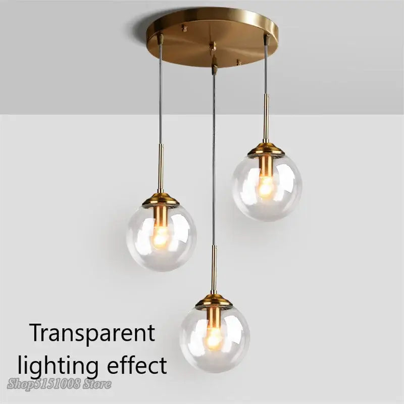 Modern brass and glass pendant lights featuring three clear glass pendant globe shades for kitchen dining room