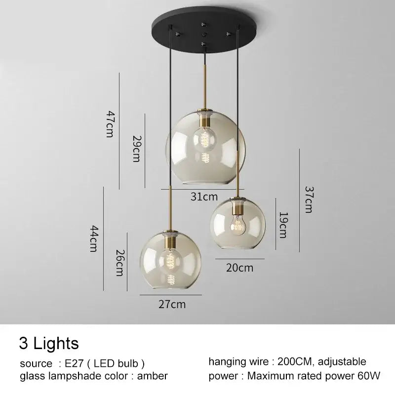 Modern brass and glass pendant lights featuring three amber-tinted glass pendant spheres for kitchen or dining room use