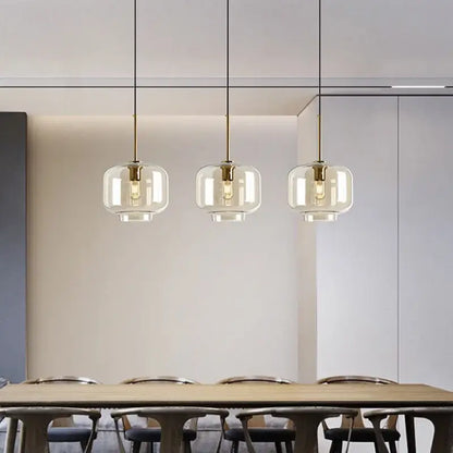 Modern brass and glass pendant lights with clear glass globes hanging above a dining table for kitchen use