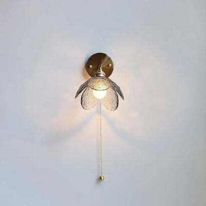 Modern brass and gray glass led wall sconce with textured flower shade and elegant pull chain for bedroom lighting