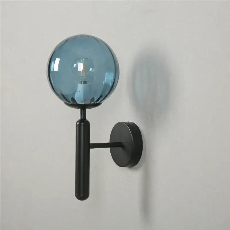 Modern brass and pink glass wall lamp with decorbites blue glass globe and black metal arm for living room decor