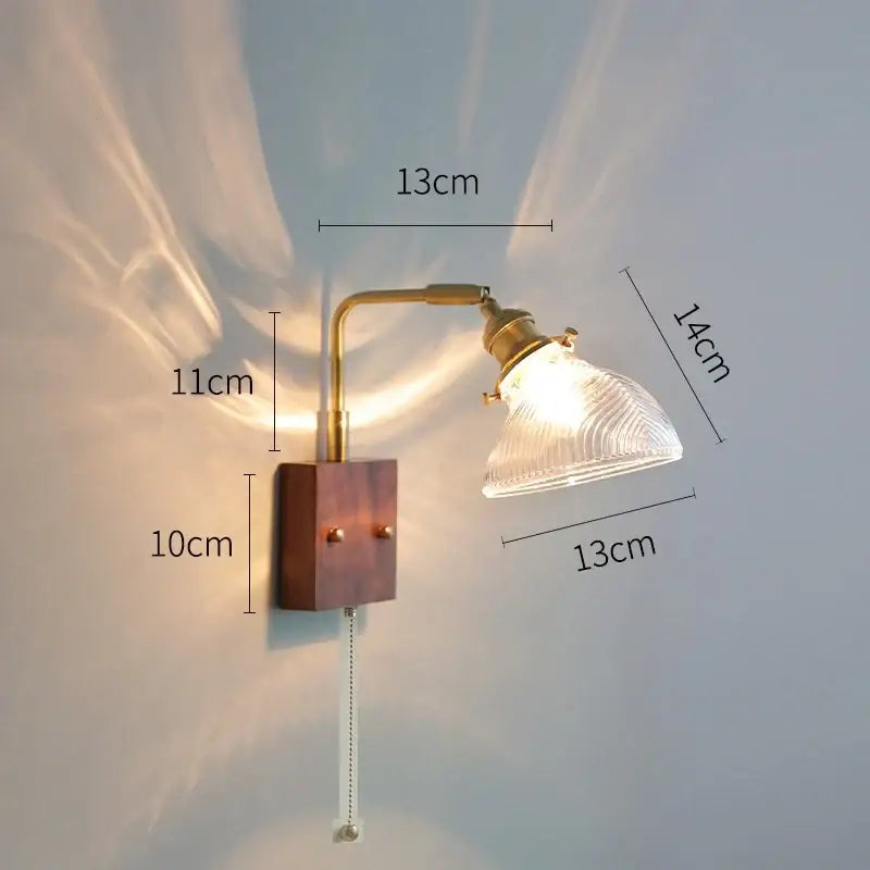 A vintage-style wall light with brass articulated arm, clear glass ribbed shade, and wooden base for bedroom decorbites clear glass