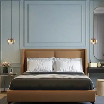 Brown upholstered bed with white pillows featured alongside modern brass and smoked glass pendant light decorbites gold wrought iron