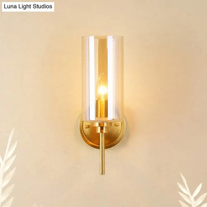 Modern brass and smoked glass wall sconce with gold tone, clear glass shade, and e26 bulb base for bedroom lighting