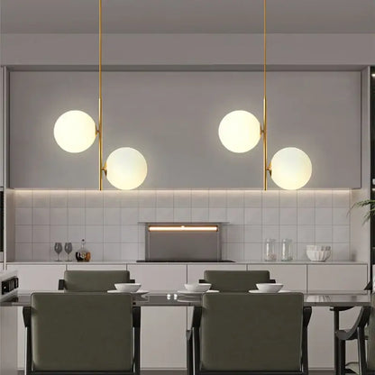 Modern brass pendant light with three smoky gray glass globe shades suspended by slender gold-toned rods for dining room