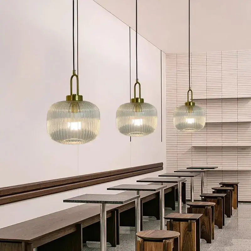 Three elegant brass finish pendant lights with ribbed striped glass globes for modern dining room lighting
