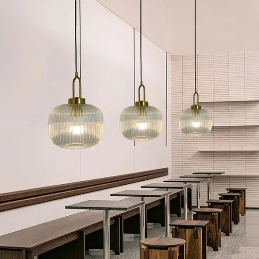 Three elegant brass finish pendant lights with ribbed striped glass globes for modern dining room lighting