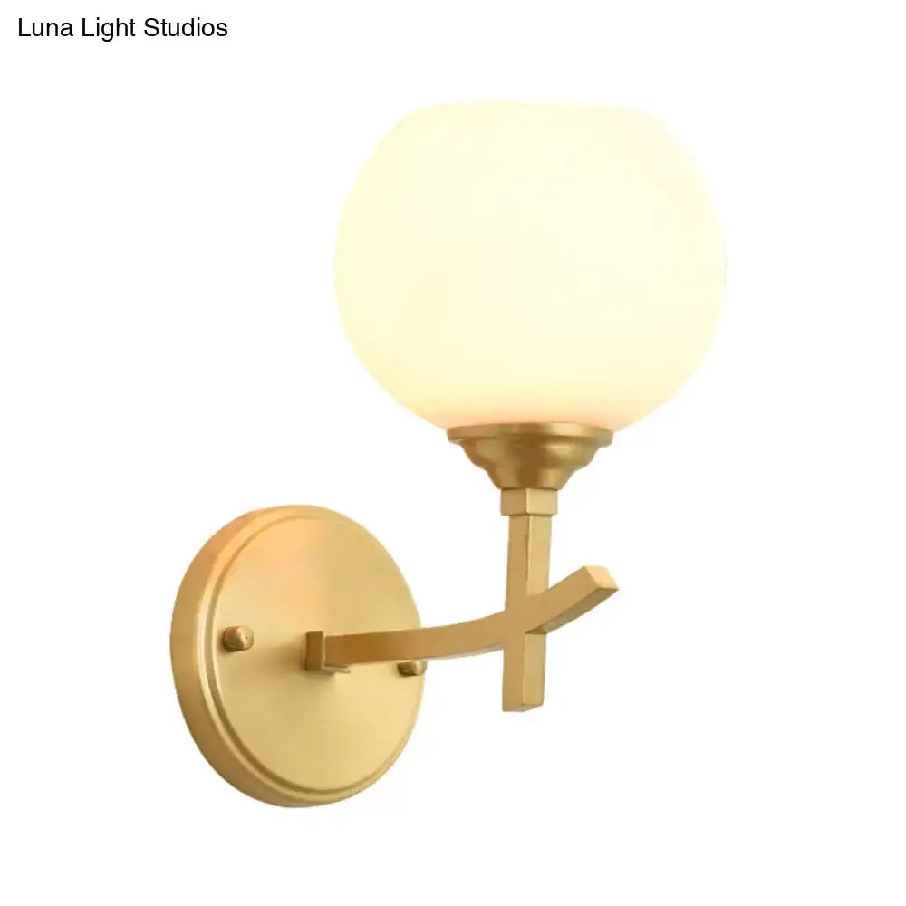 Modern brass armed wall sconce with gold finish and opal glass shade for elegant bedroom lighting