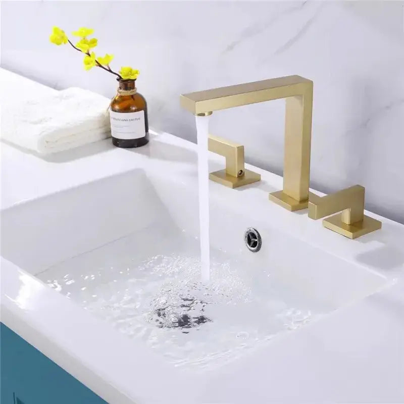 Modern brass black basin faucet with sleek gold-toned angular design and three separate handles for bathroom use