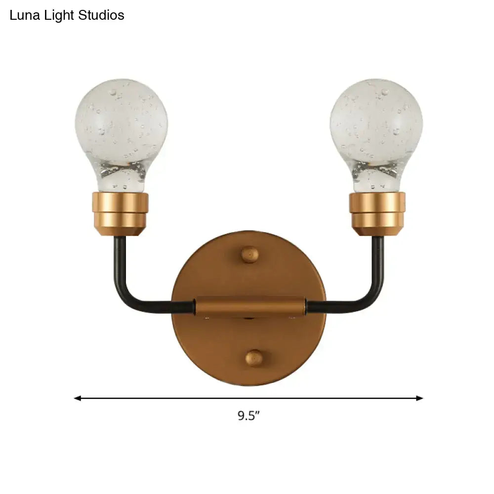 Modern brass and black metal two-light wall light with bulb shaped sconce design and seeded glass bulbs for bedroom use