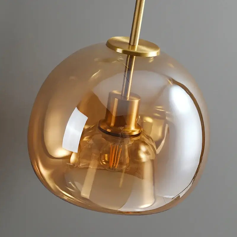 Modern brass and black glass ball led ceiling light featuring an amber-tinted decorbites glass ball with polished brass finish