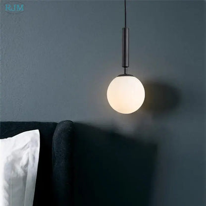 Black cylindrical pendant light featuring a frosted glass globe in modern brass and black glass ball led decorbites design