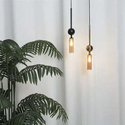 Two modern brass and black glass pendant lights with spherical tops and cylindrical shades featuring led bulb design style