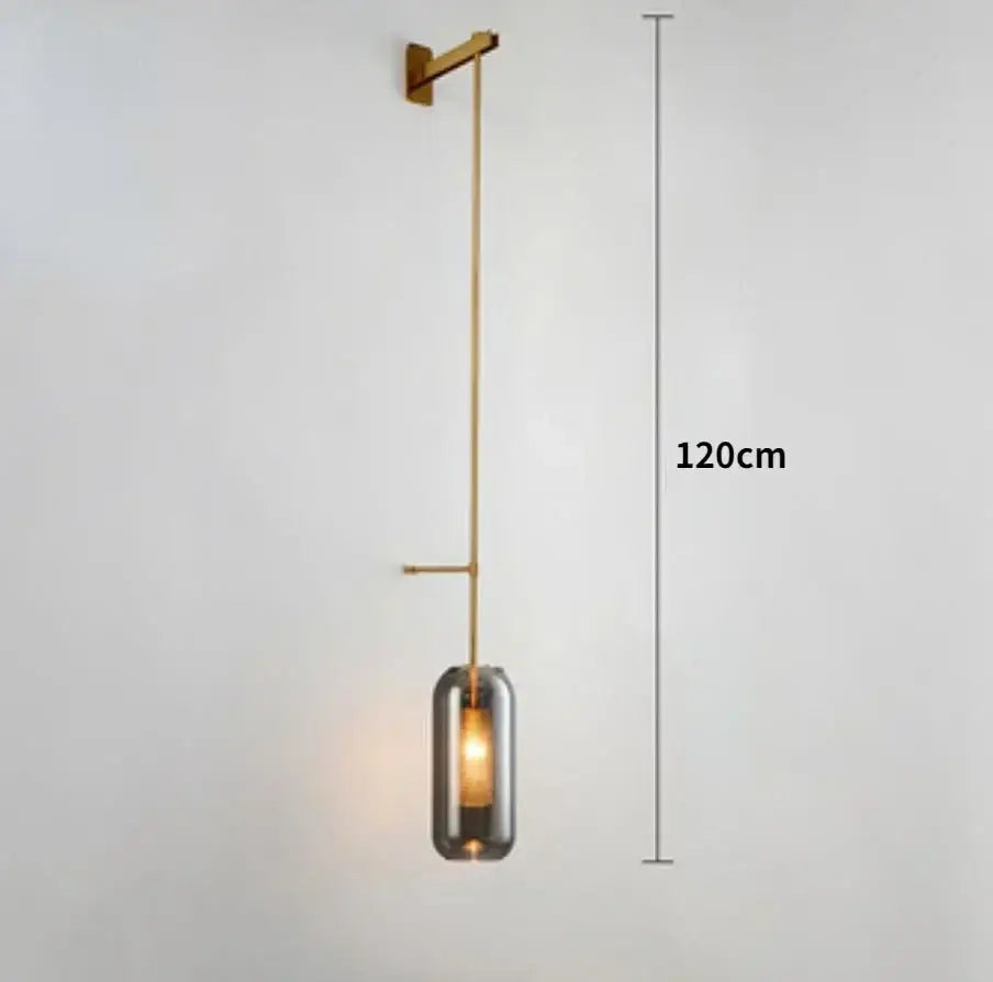 A sleek 120cm modern wall sconce light with brushed brass finish and cylindrical smoked glass shade for bedrooms