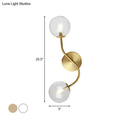 Modern brass clear tan glass wall lamp with gold-toned twisted metal arm and two clear glass globe shades bulb base