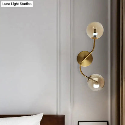Modern brass wall lamp with clear tan glass globes and gold-toned bulb base for stairway lighting with two lights