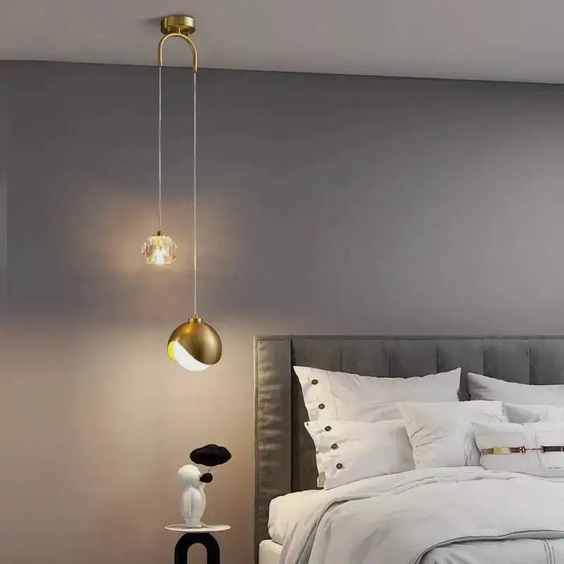 A modern brass crystal ball pendant light with a crystal-encrusted bulb and sleek curved design for bedroom decorbites decor
