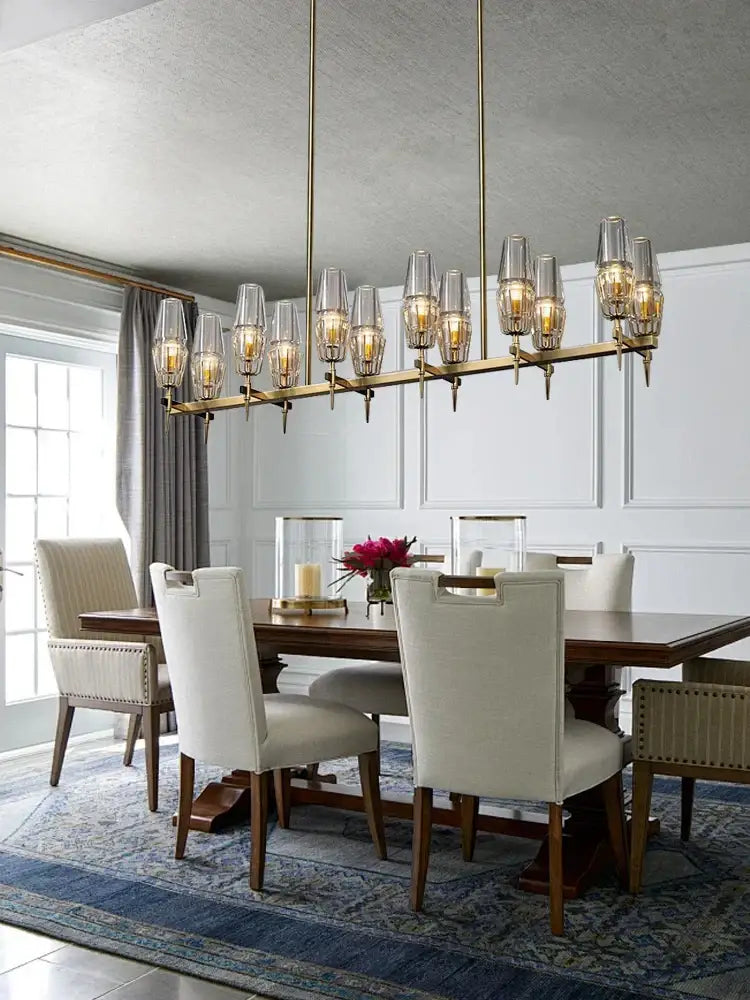 Modern brass crystal bronze pendant lamp with clear glass shades and warm glowing bulbs for dining room decorbites