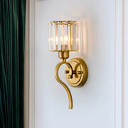 Modern brass crystal cylinder wall sconce with gold-toned curved arm and cylindrical crystal block cylinder shade for bedroom light