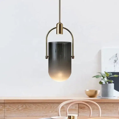 A modern brass decorbites bucket chandelier with a brass frame and cylindrical glass shade featuring amber tones