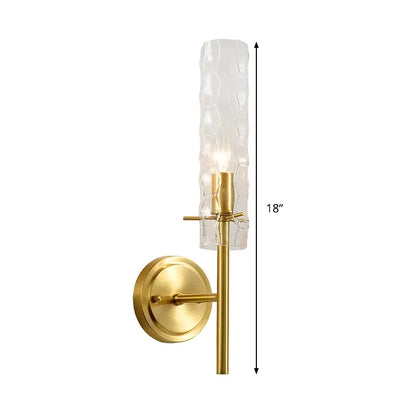 A sleek 18-inch modern brass wall light with dimpled blown glass cylinder and frosted textured shade for bedrooms